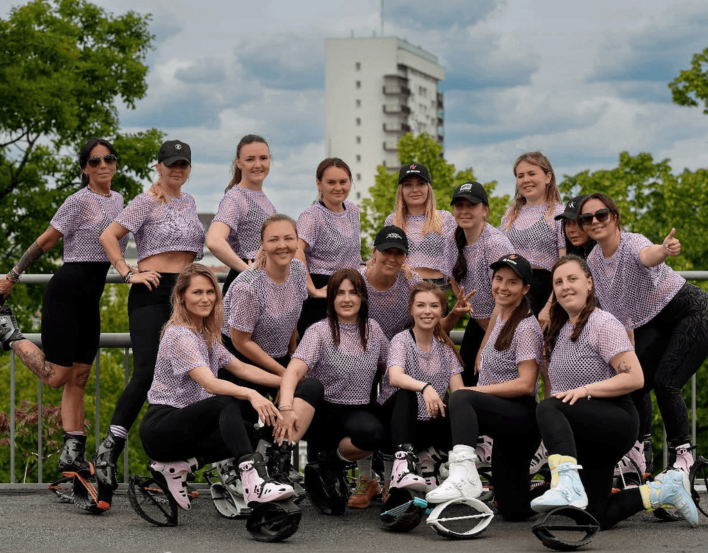 Group of people in matching outfits posing outdoors with a building and trees in the background