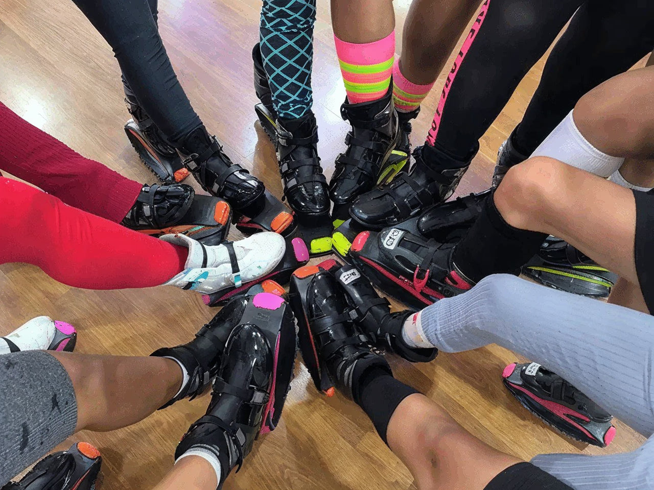 Multiple pairs of roller skates on a wooden floor