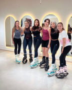 Group of six women posing together in a modern indoor setting with glowing arches.