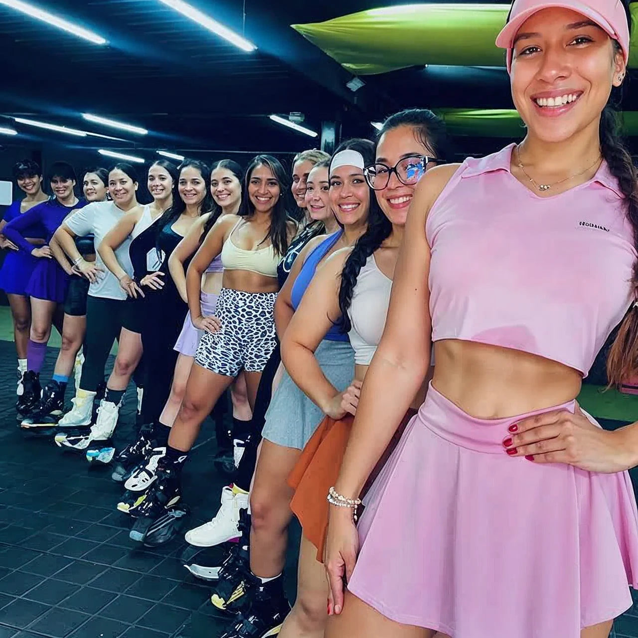 Group of women posing together in a dance studio, wearing athletic wear and roller skates.