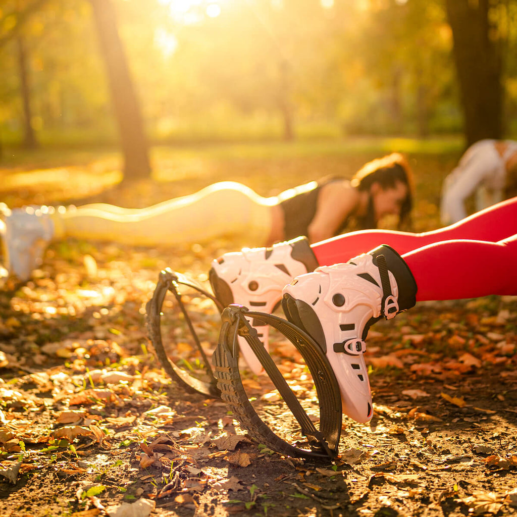 Close-up of people doing planks outdoors while wearing Fit Boots Rebound Boots in pink