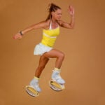 Woman jumping while wearing blue and yellow Fit Boots Rebound Boots