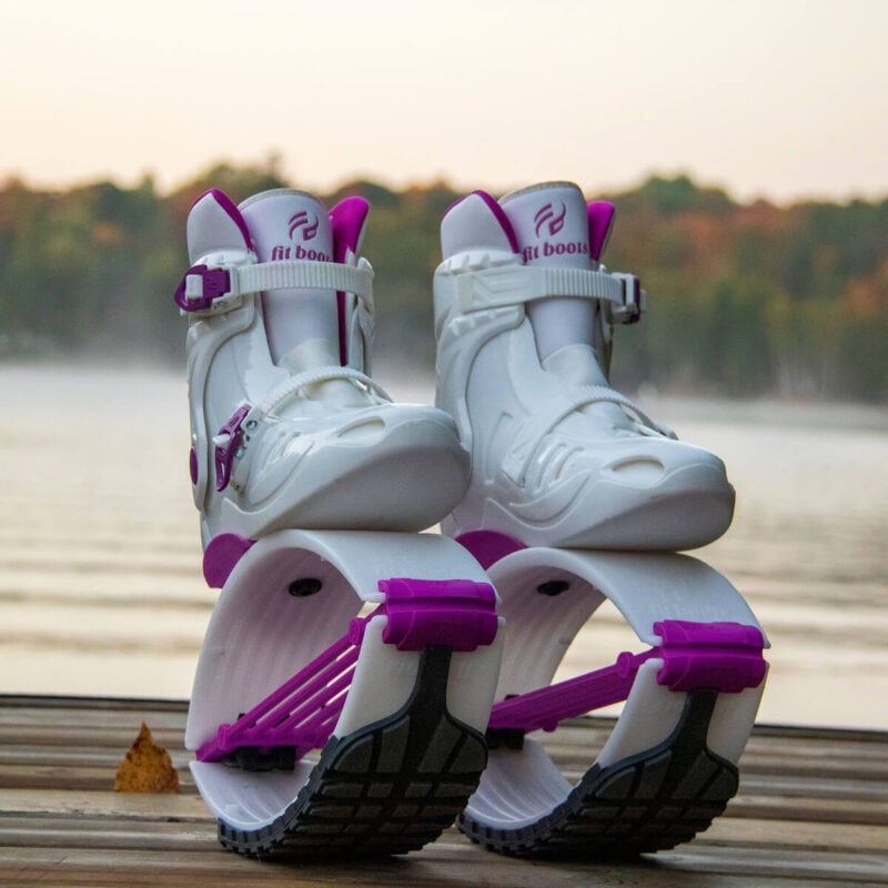 Pair of white and purple Fit Boots Rebound Boots placed on a wooden surface near a lake